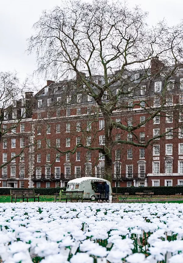 A historic London red-brick building beside a garden